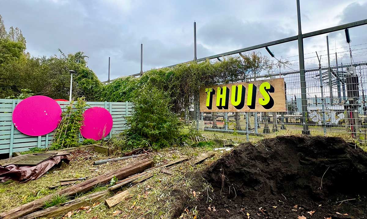 Photo of a sign reading 'Thuis' in front of a power plant in Amsterdam Noord